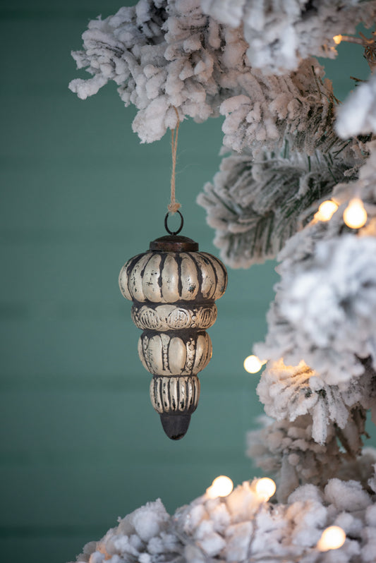 Antique silver icicle Christmas ornament with black accents hanging on a frosted tree