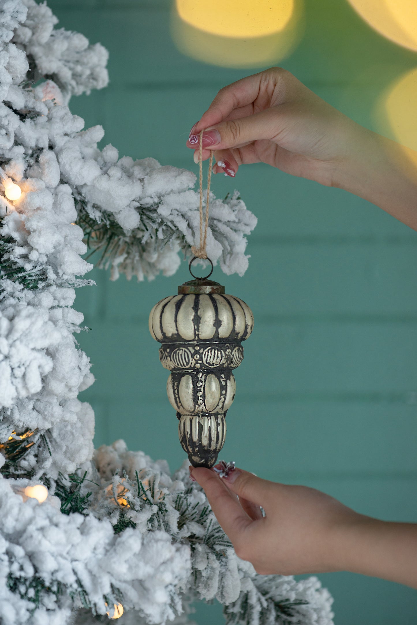 Vintagestyle glass Christmas ornament antique gold with dark accents hanging on frosted tree