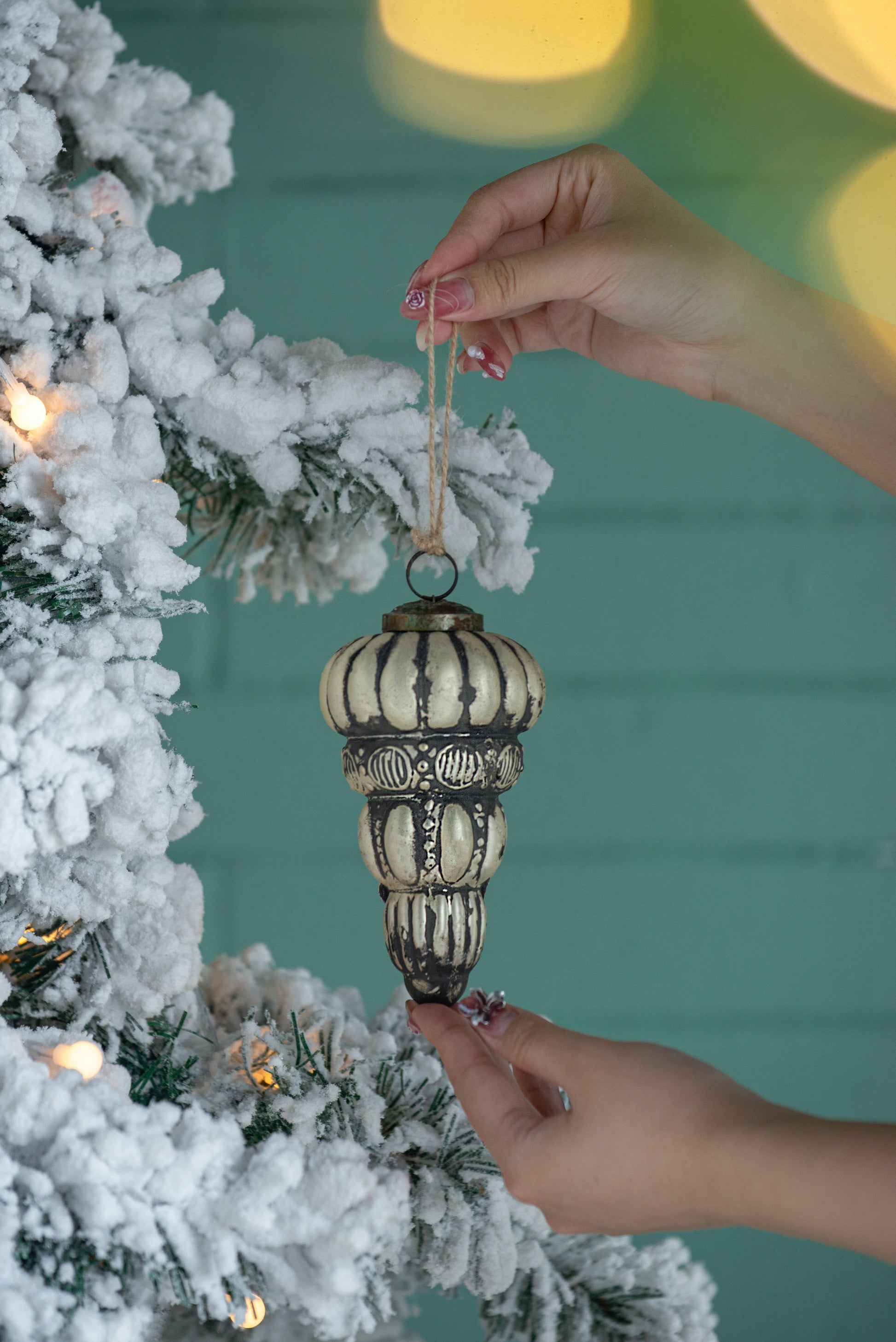 Vintagestyle glass Christmas ornament antique gold with dark accents hanging on frosted tree