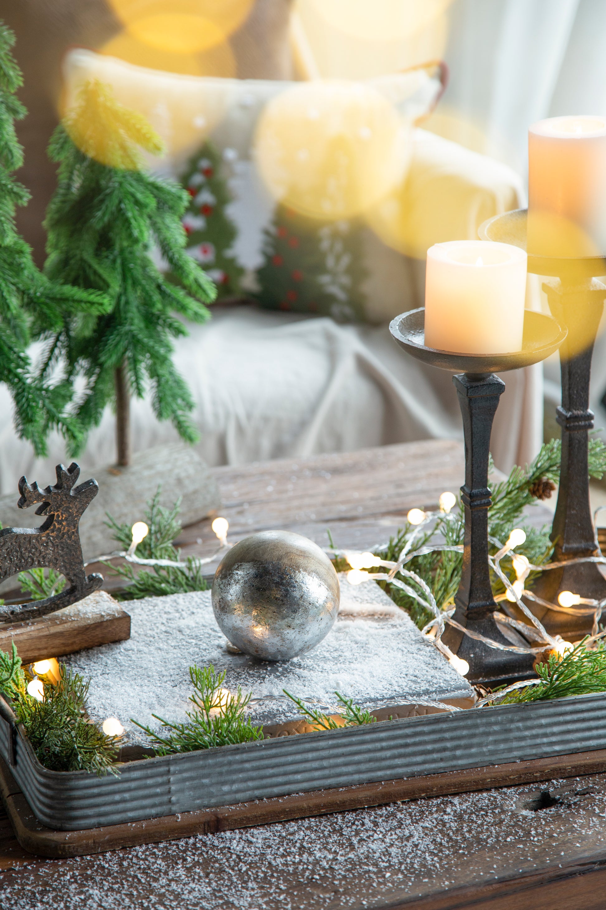 Rustic galvanized metal tray holding a silver Christmas ornament pine sprigs and fairy lights