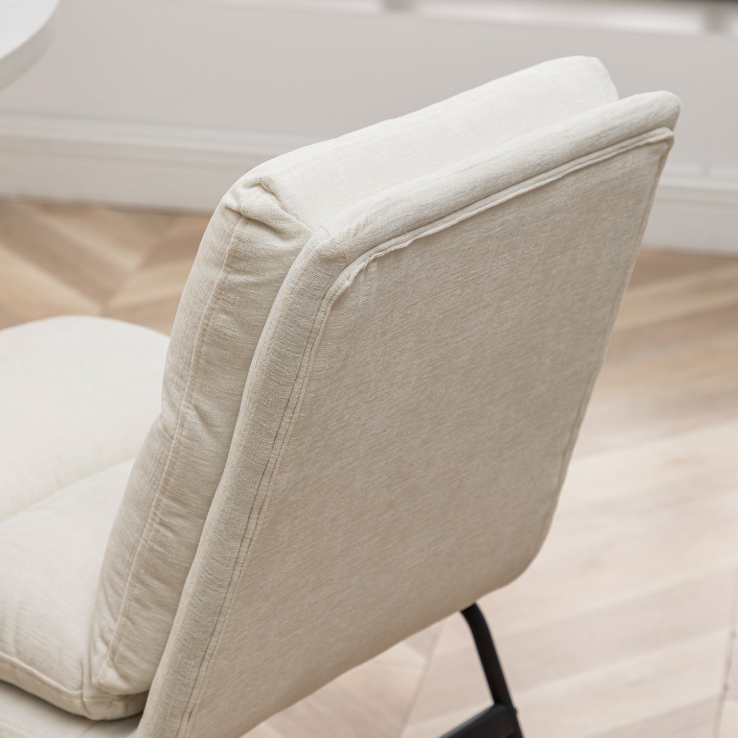 Closeup of a beige textured fabric accent chair back with visible stitching