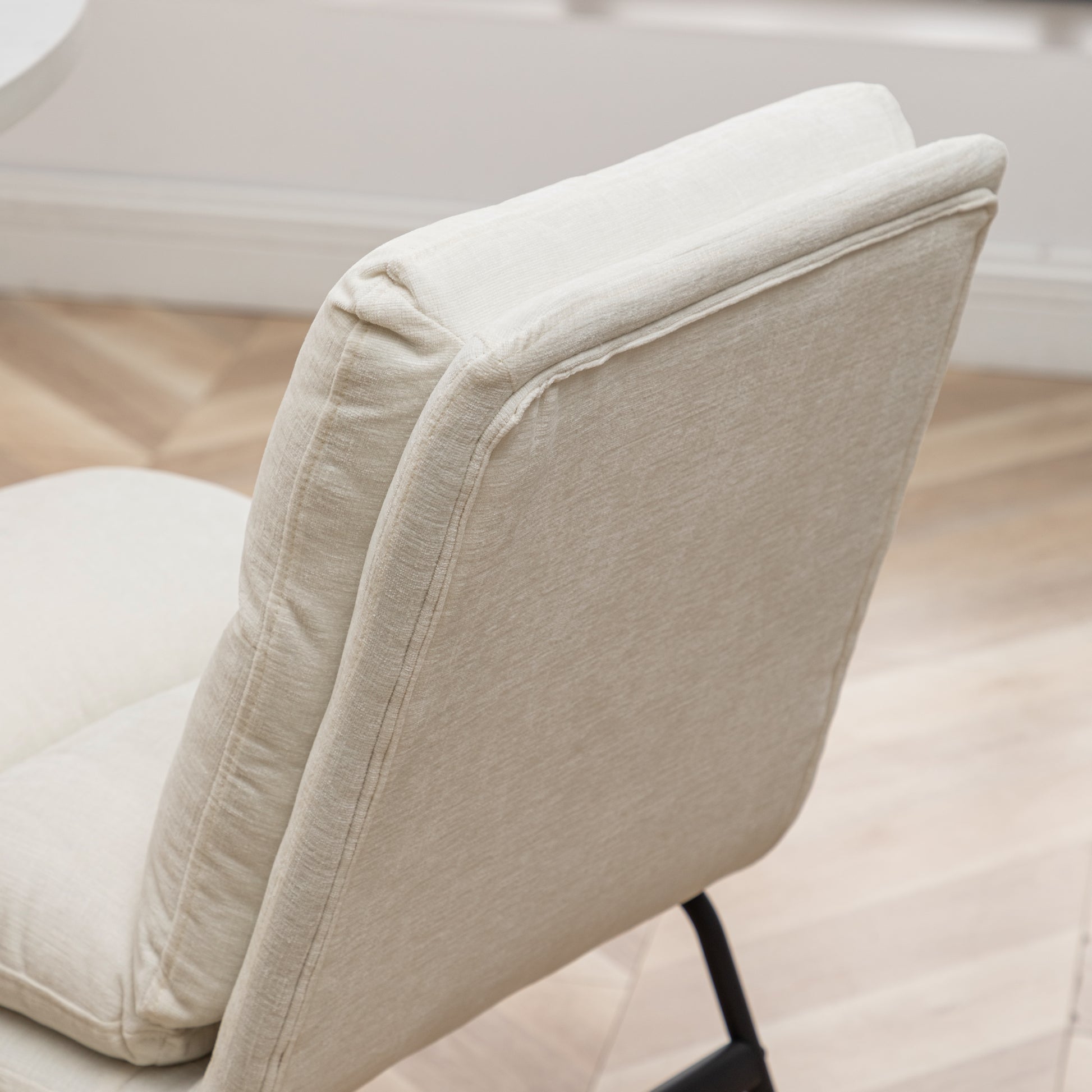 Closeup of a beige textured fabric accent chair back with visible stitching