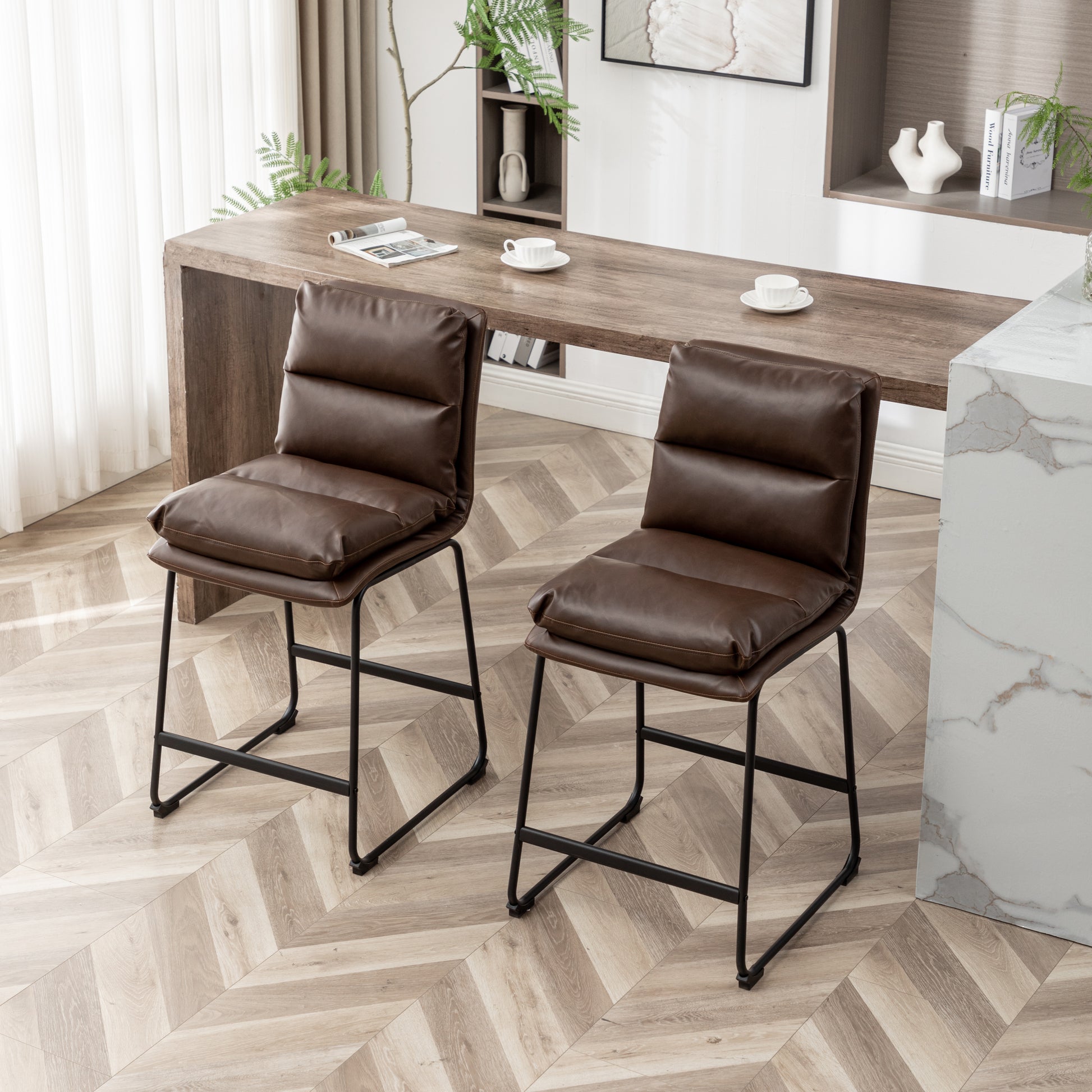 Two brown faux leather bar stools with padded seats and backs on black metal legs