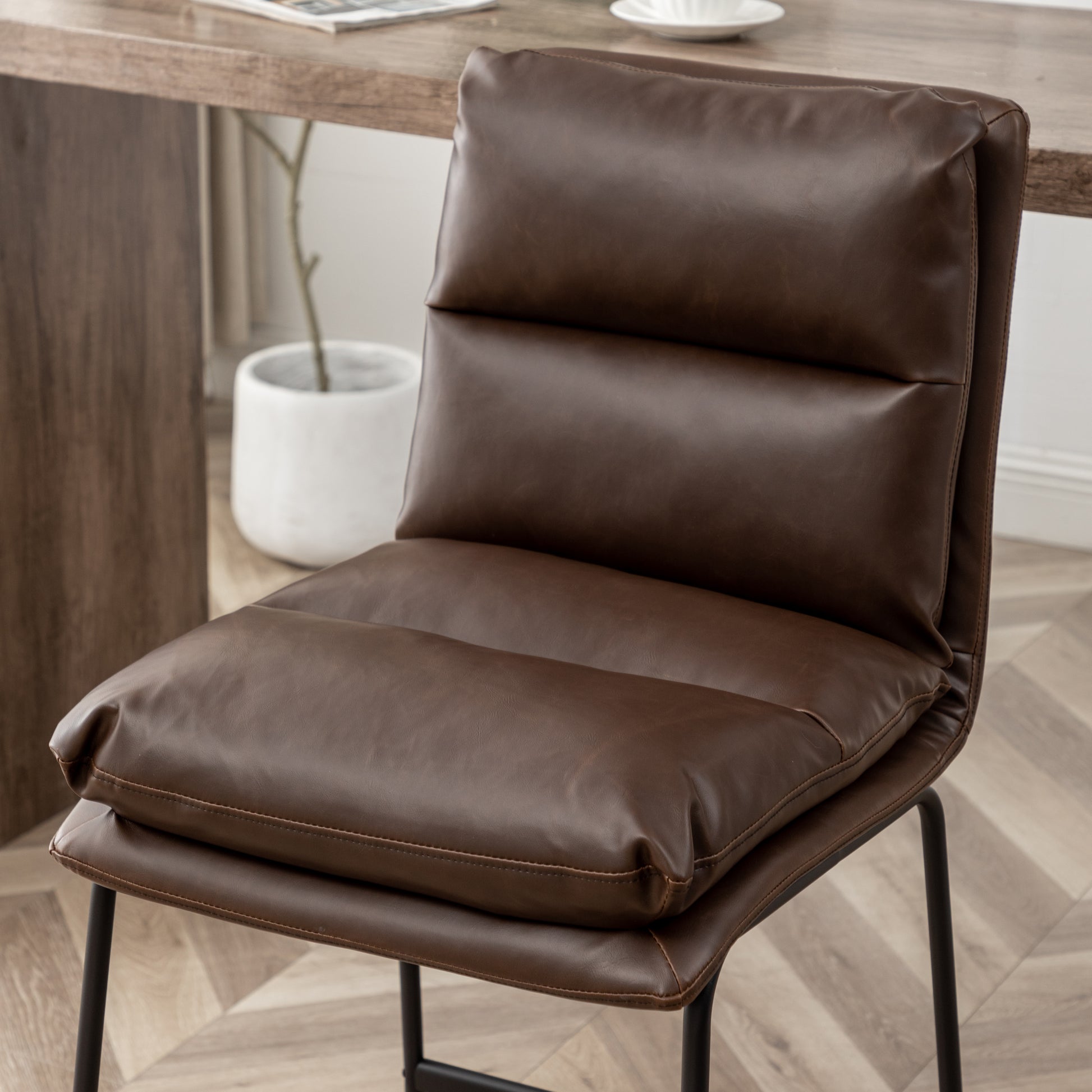 Tufted brown faux leather dining chair with black metal legs for a modern aesthetic