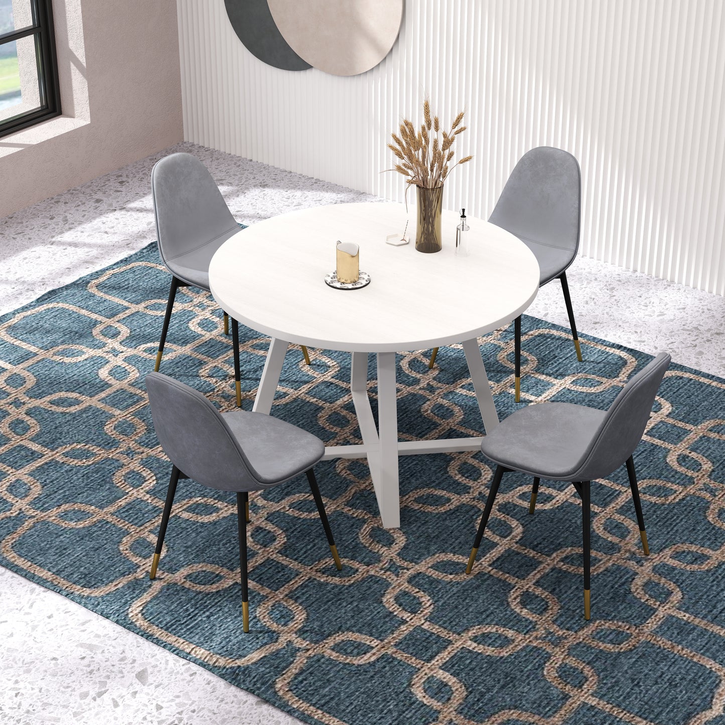 Round white dining table with four grey upholstered chairs and geometric rug