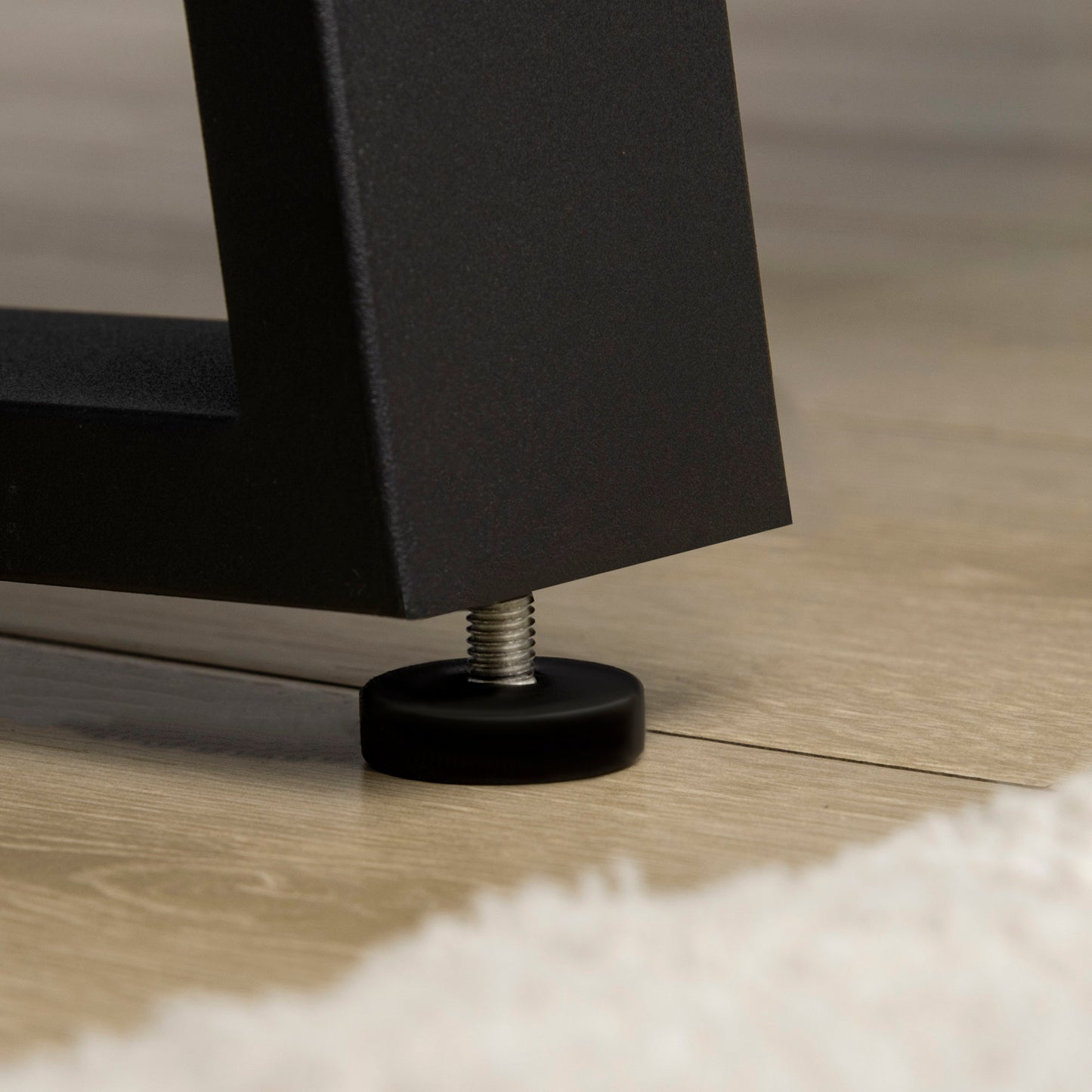Black metal table leg with adjustable leveler on wood floor