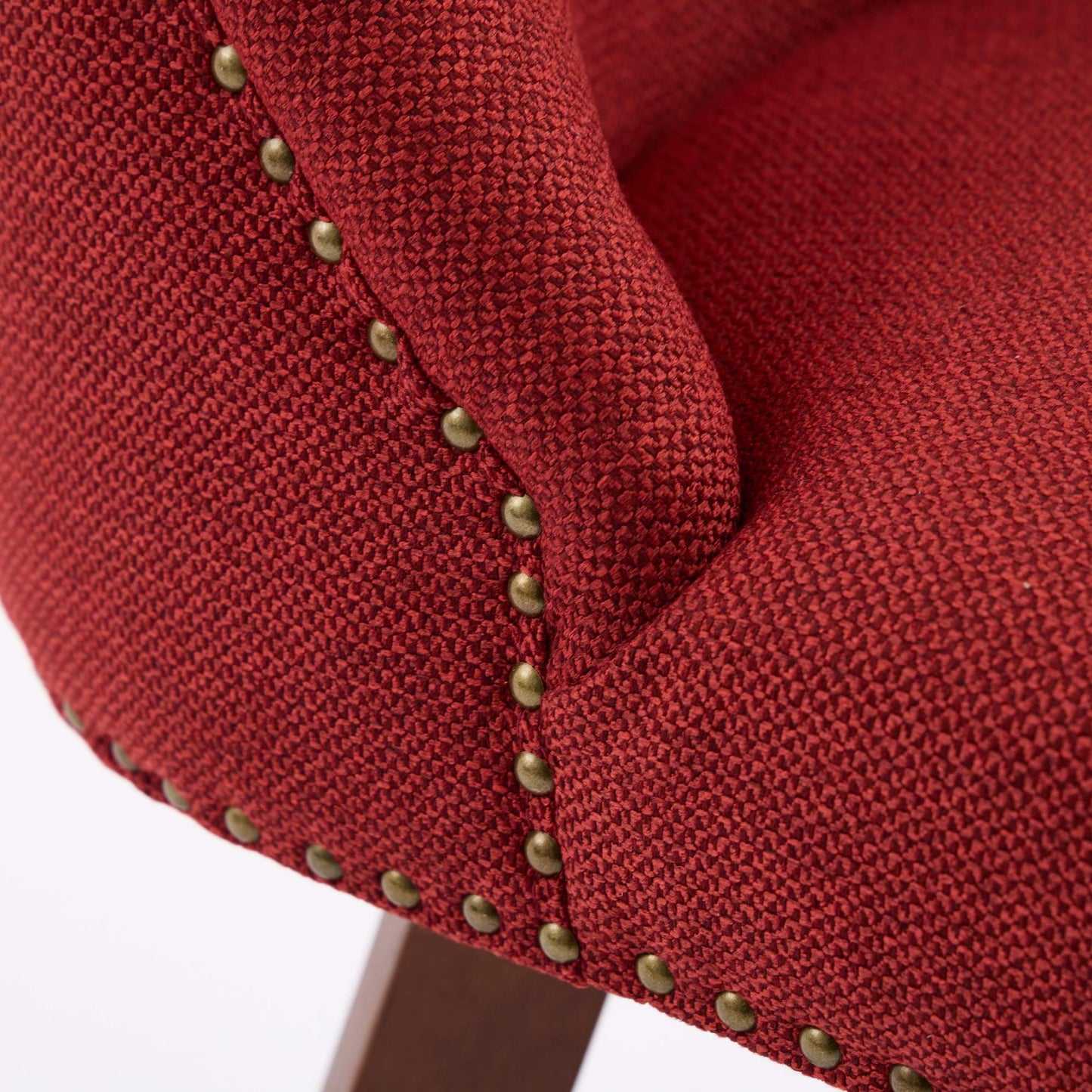 Closeup of red textured fabric on a chair with brass nailhead trim