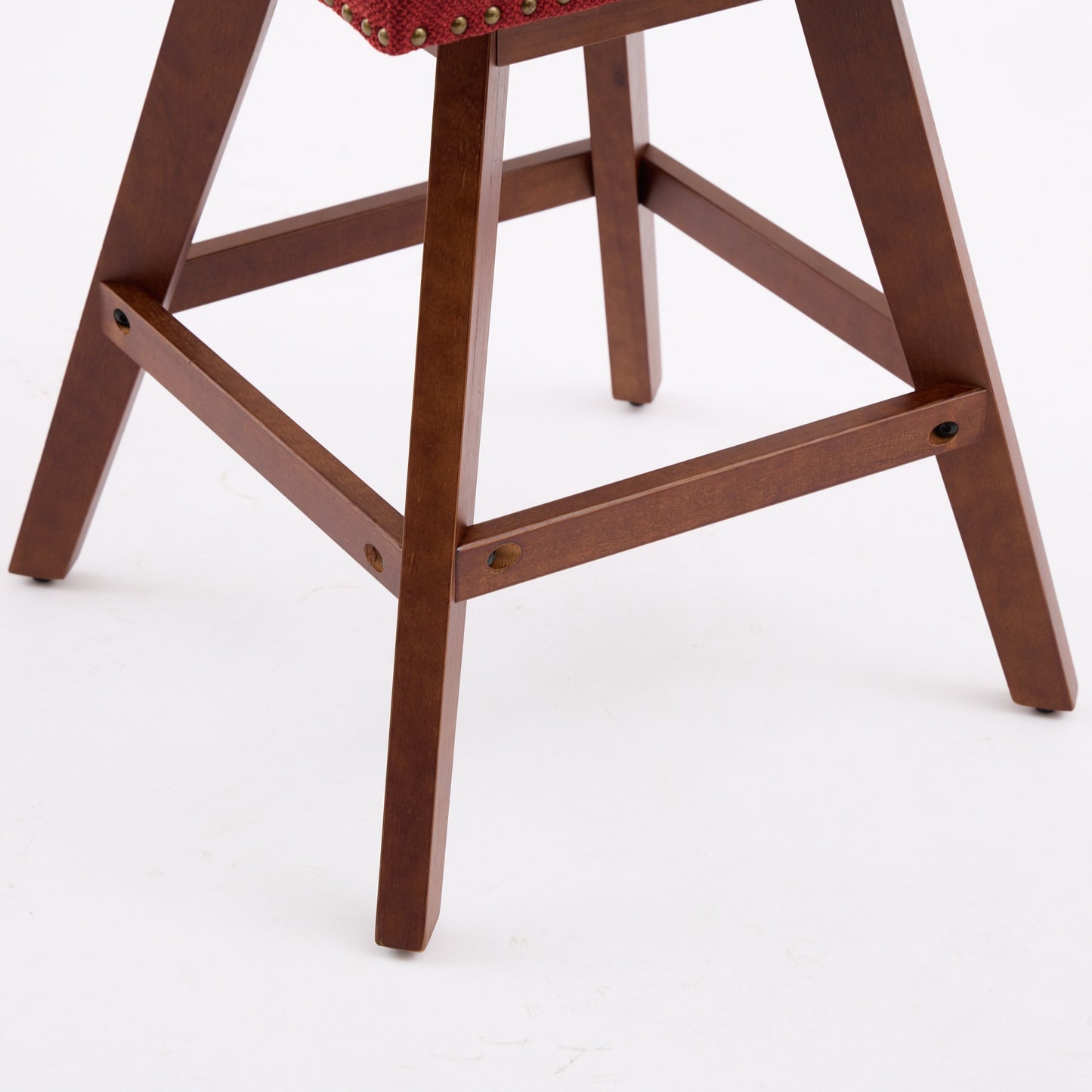Closeup of a red upholstered bar stool with wooden legs and brass tack trim