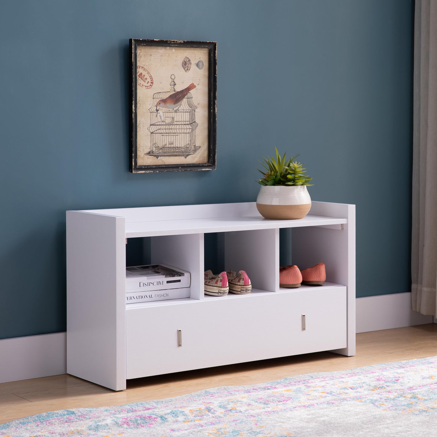 White shoe storage bench with two open cubbies holding shoes and a drawer