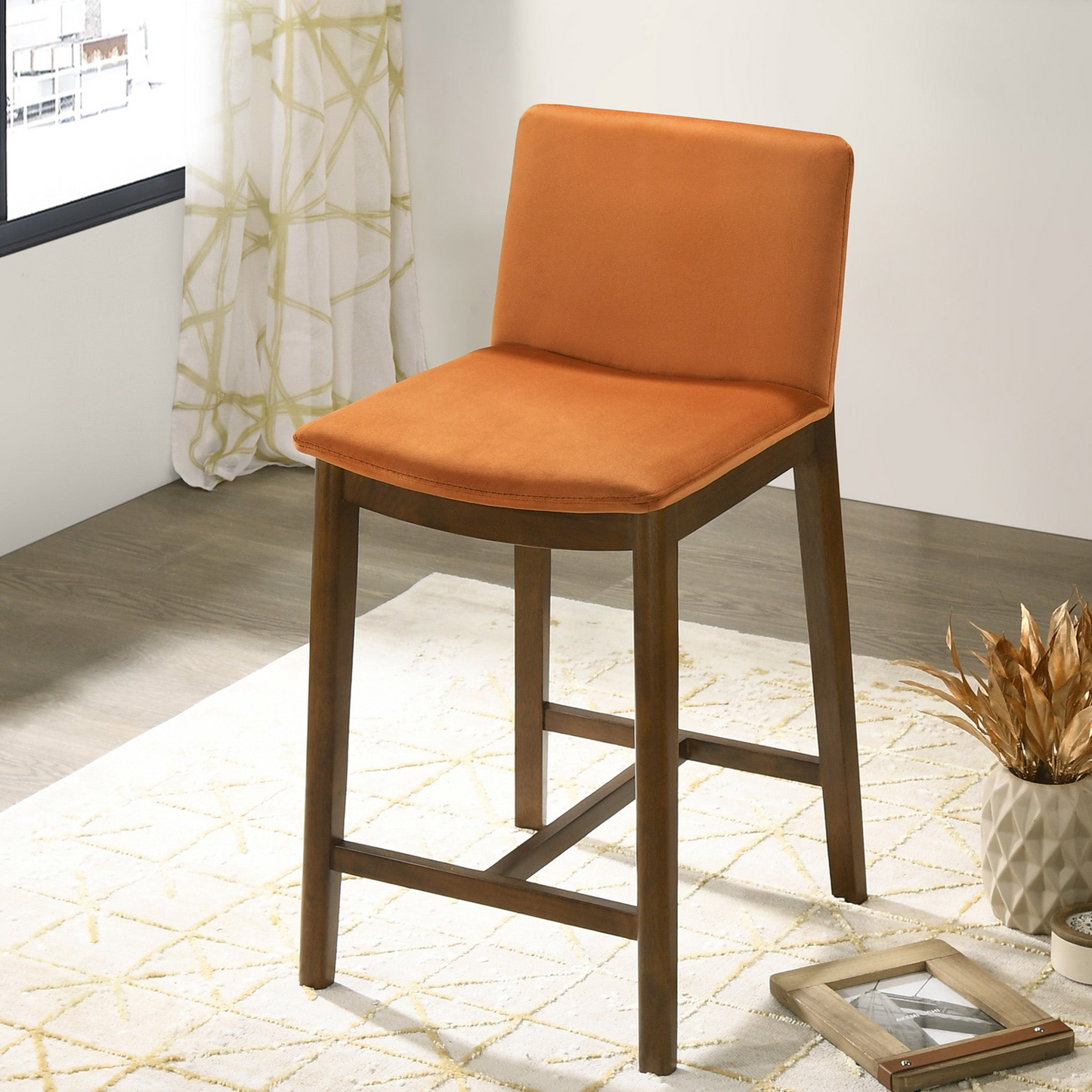 Orange upholstered counter stool with dark wood legs and a modern design