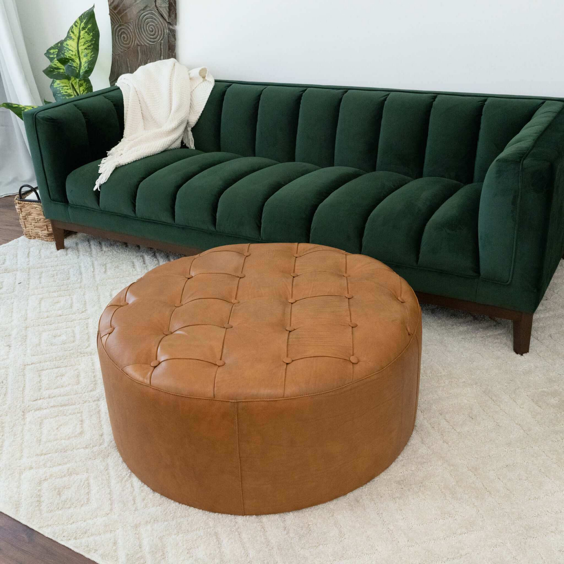 Deep green velvet sofa with channel tufting and a white knit throw blanket