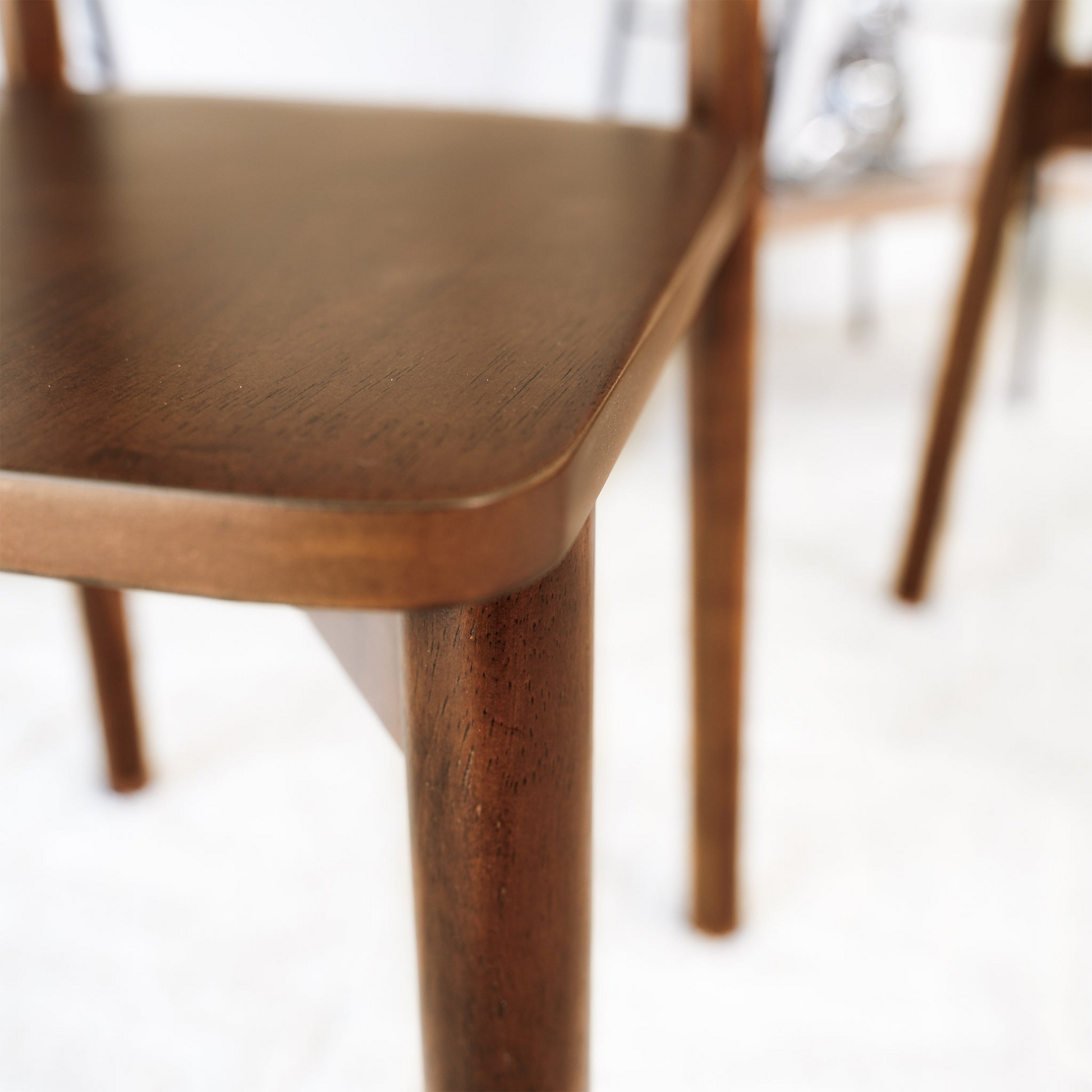 Closeup of a dark wood modern dining chair seat edge with rounded corners