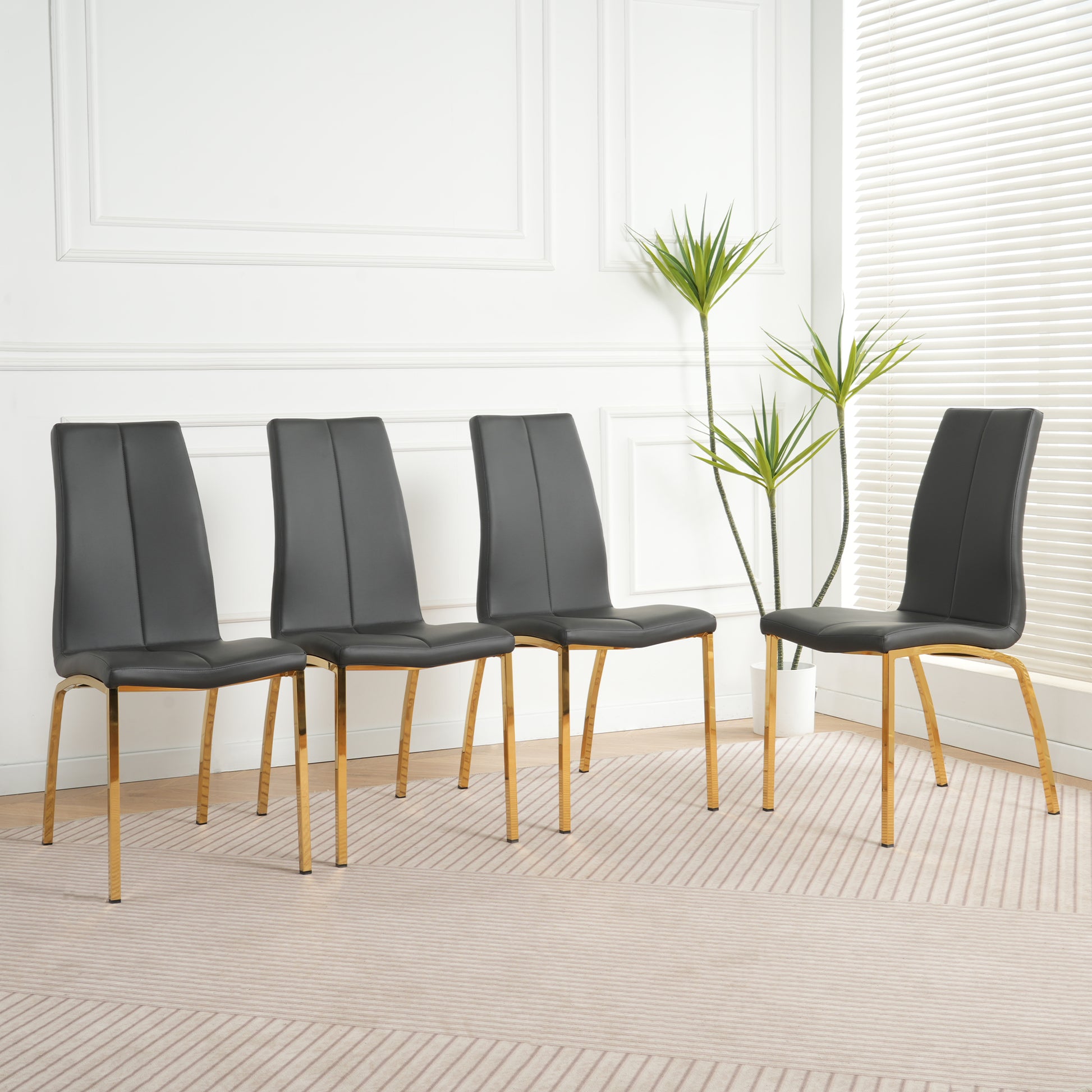 Four black faux leather dining chairs with gold metal legs