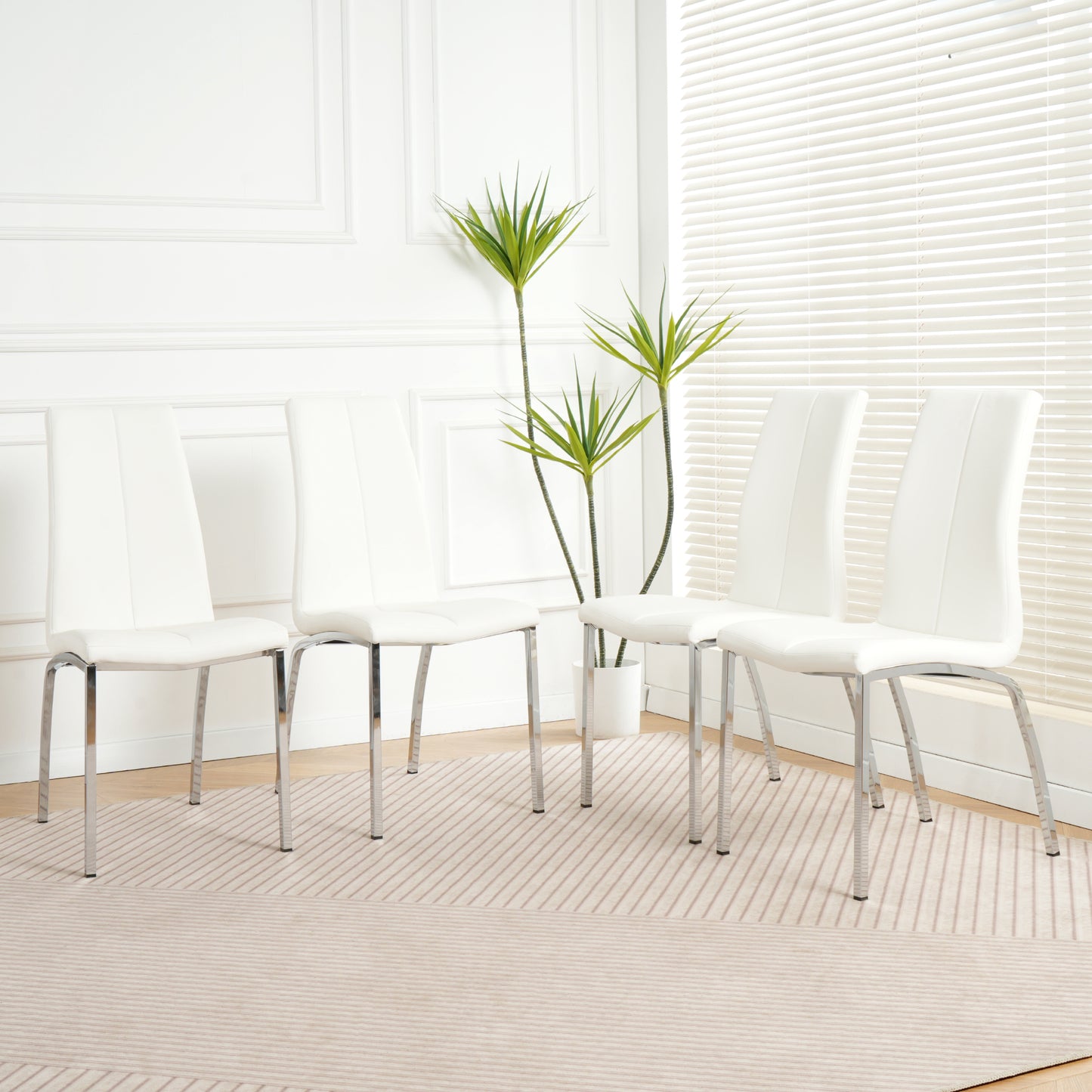 Four white modern dining chairs with chrome legs arranged on a striped rug