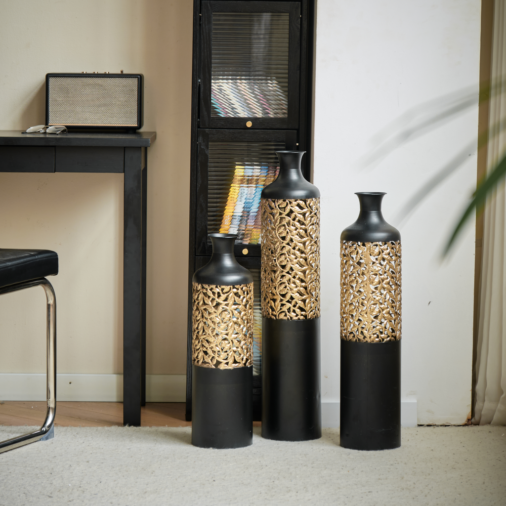 Three black and gold ornate decorative vases of varying heights
