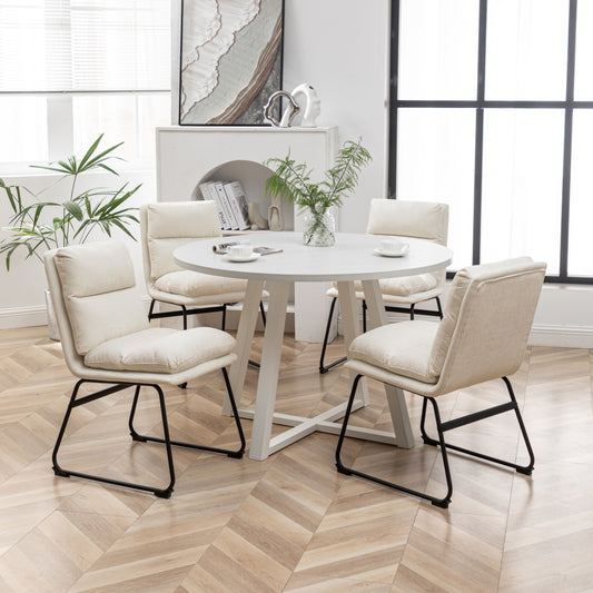 Modern cream fabric dining chairs with black metal legs set around a white round table