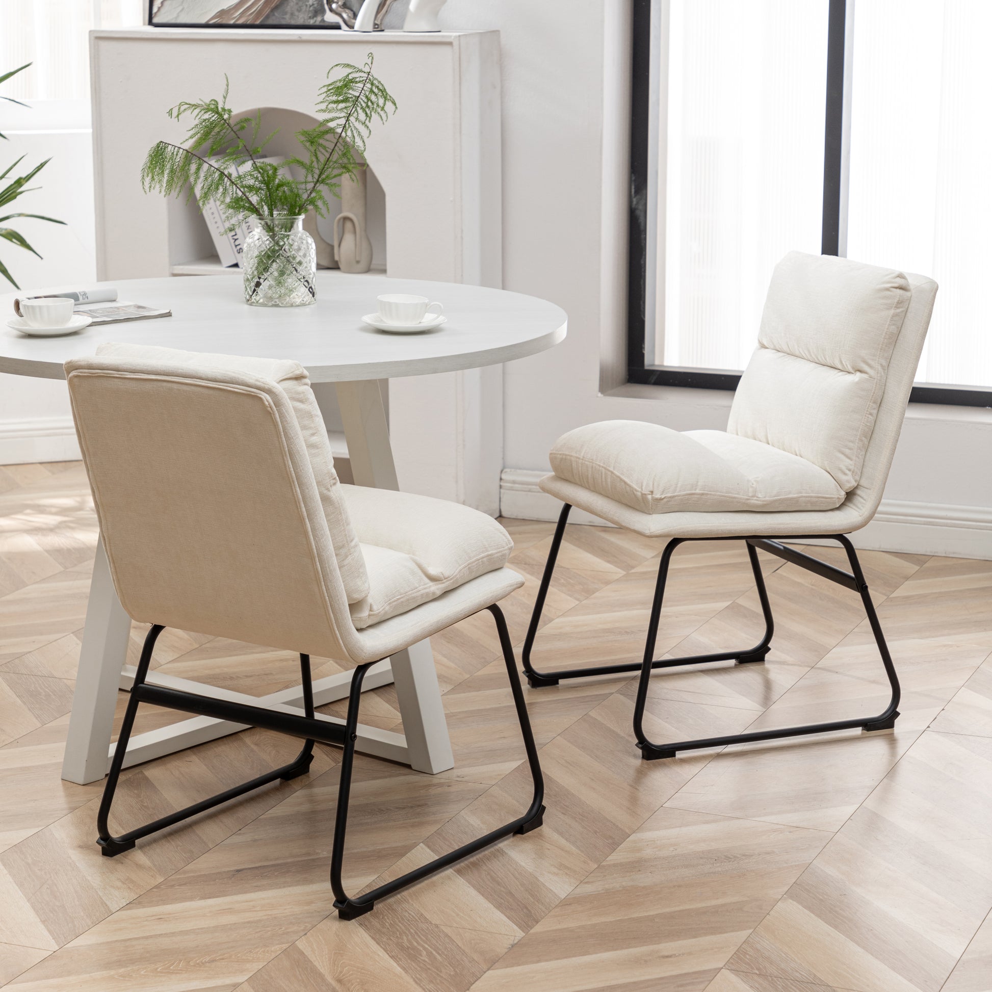 Upholstered accent chairs in a neutral cream fabric with black metal legs perfect for modern dining spaces