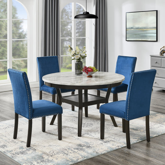 Round marble top dining table with dark wood base and four blue velvet dining chairs with silver nailhead trim