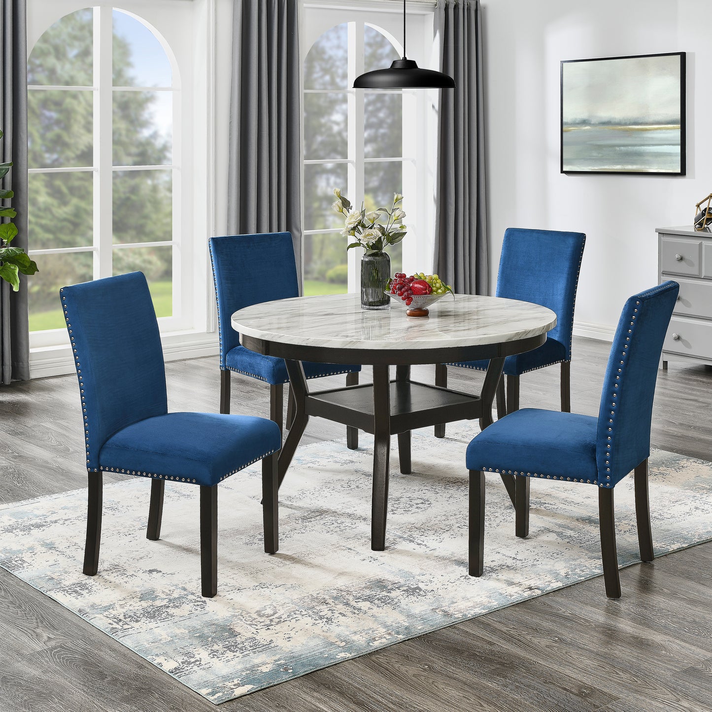Blue velvet dining chairs with silver nailhead trim surrounding a round marble top table