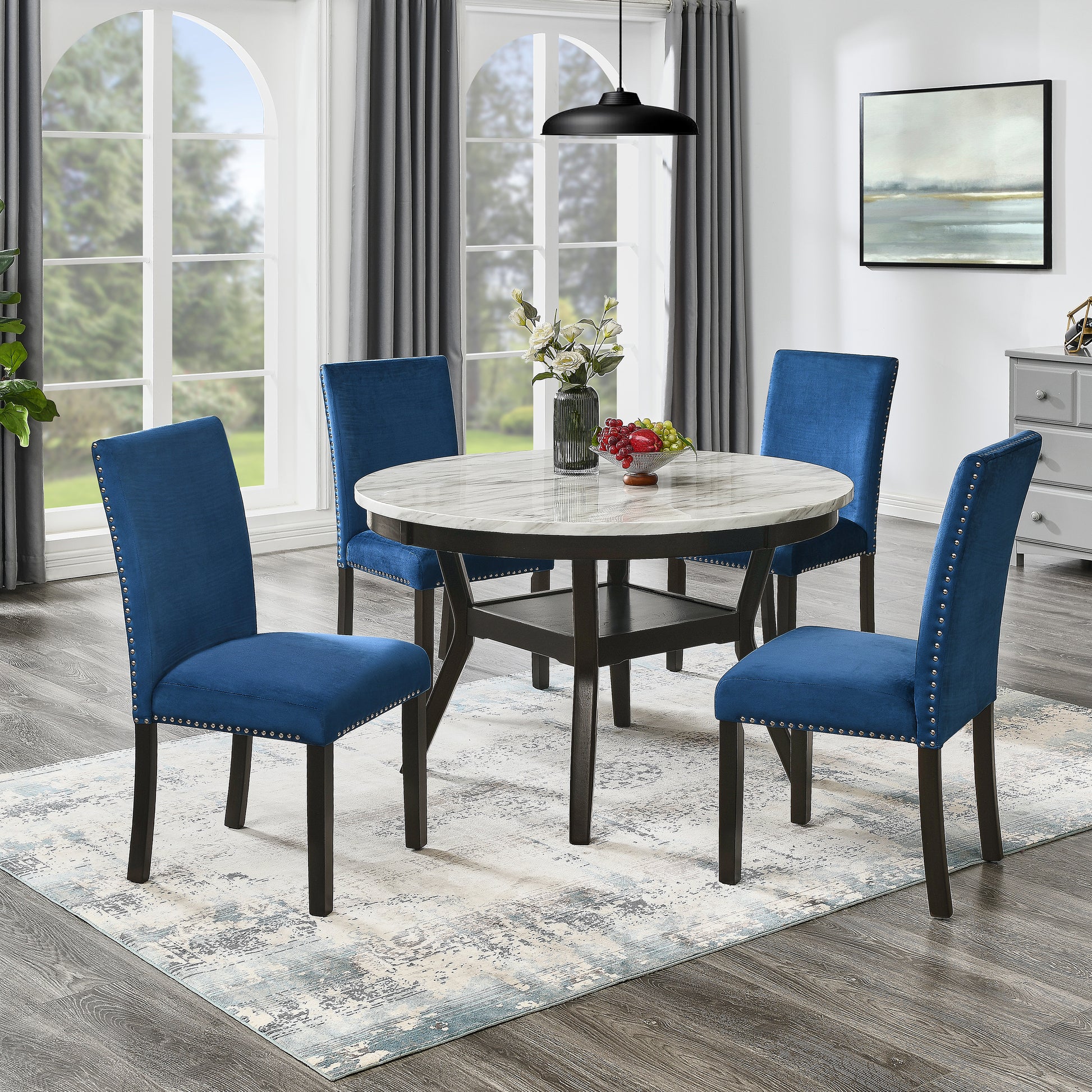 Blue velvet dining chairs with silver nailhead trim surrounding a round marble top table