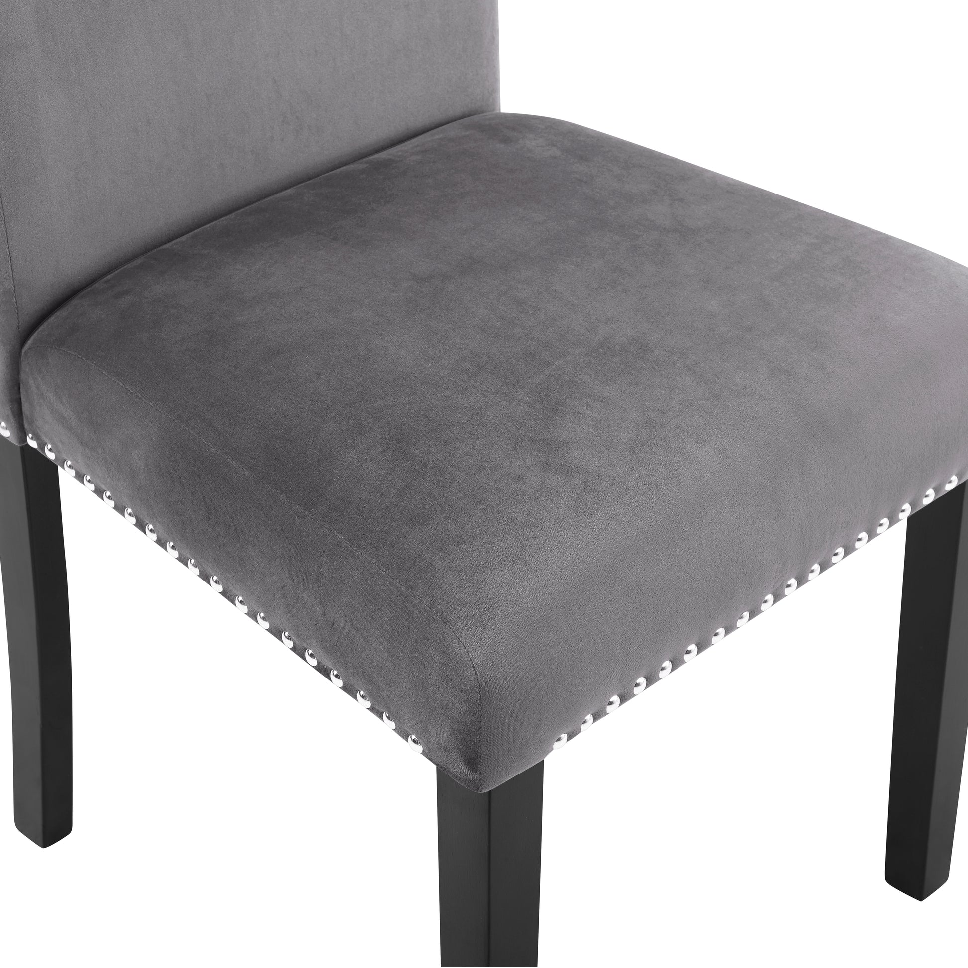 Closeup of a grey velvet dining chair seat with silver nailhead trim and dark wood legs