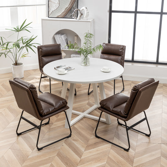 Modern dining set with a round white table and four brown faux leather chairs on a wood floor