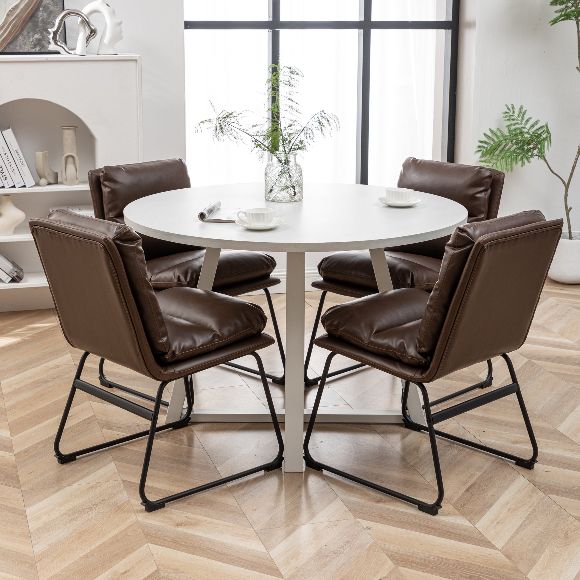 Brown faux leather dining chairs with black metal legs around a white round table