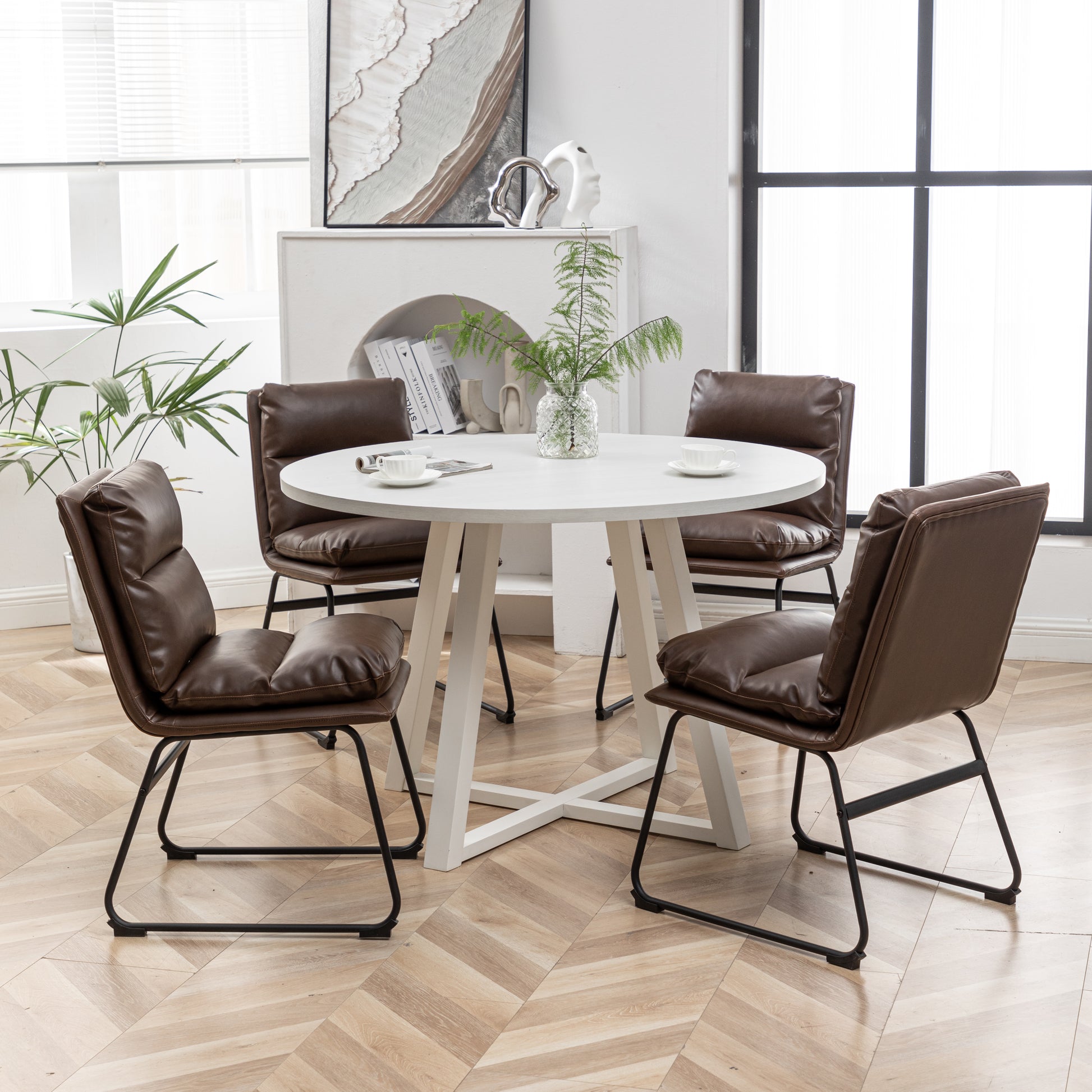 Set of  brown faux leather dining chairs with black metal legs arranged around a white round table