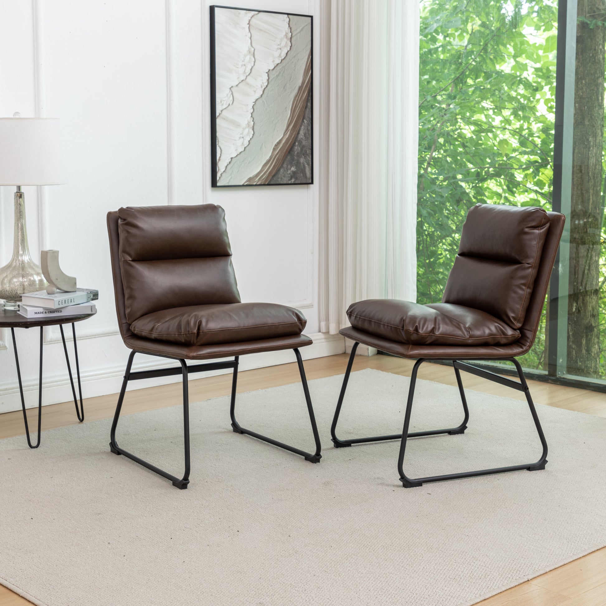 Two brown faux leather accent chairs with black metal frames and plush cushions