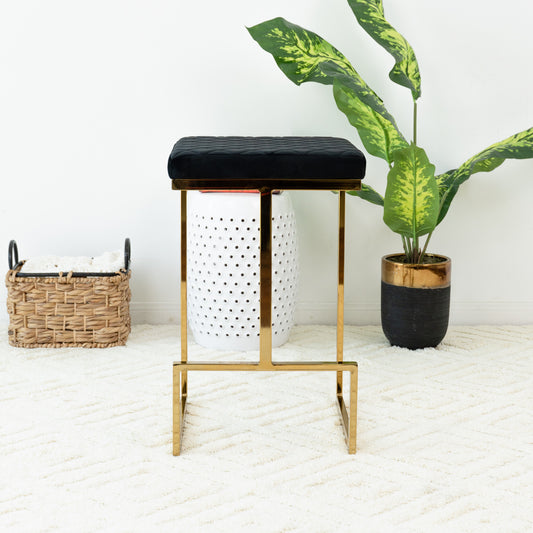 Quilted black velvet bar stool with a polished gold frame and a plush seat