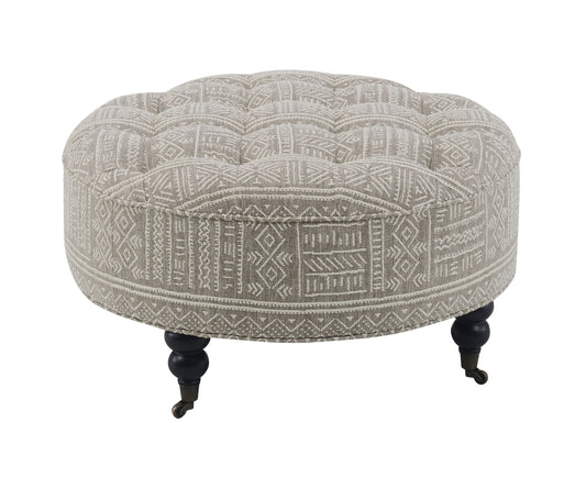 Tufted round ottoman with tribal geometric pattern in neutral tones black legs and casters