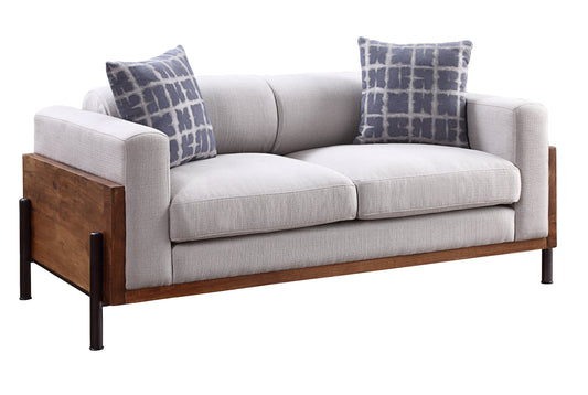 Modern grey fabric loveseat with two patterned throw pillows and wood accents