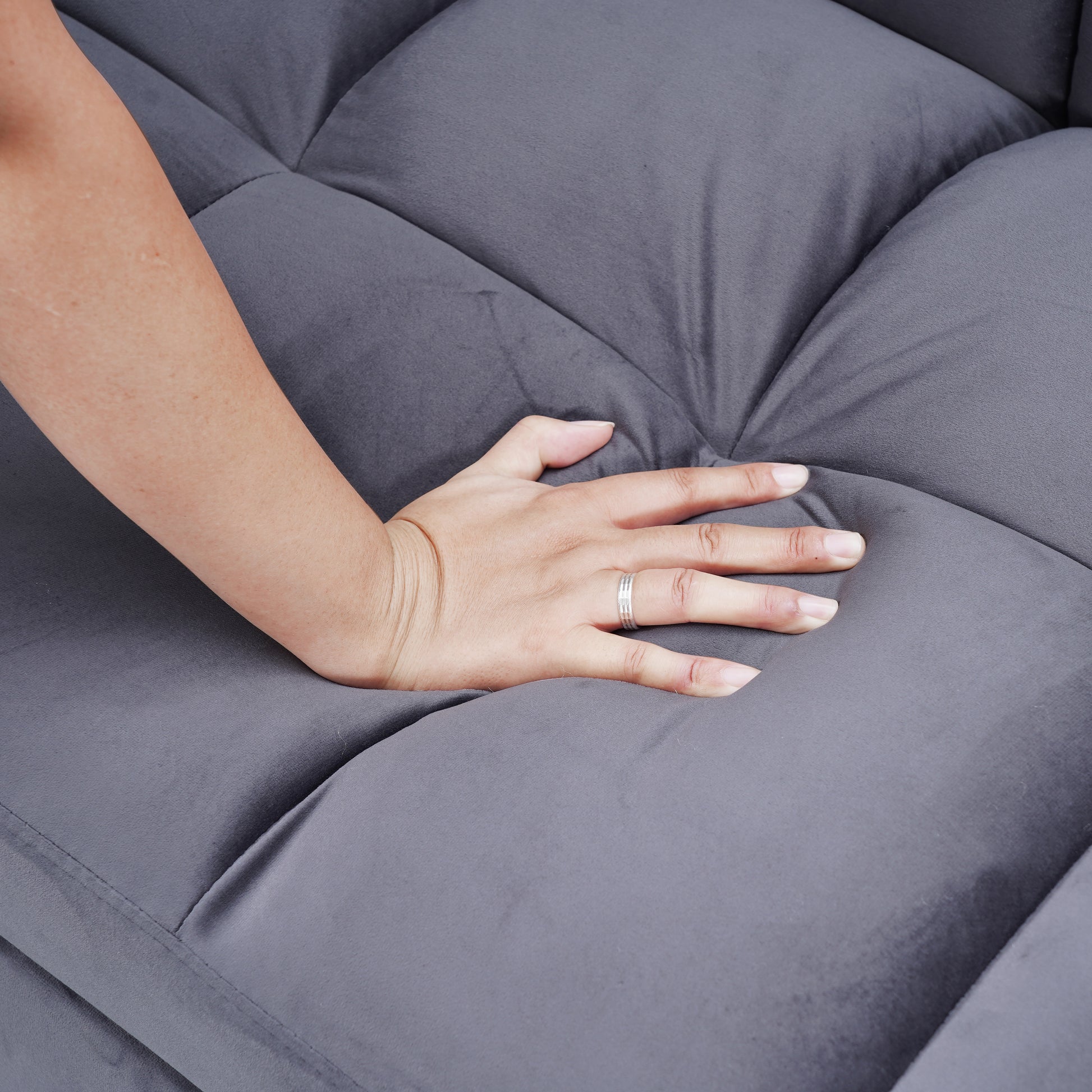 Hand pressing into soft grey velvet sofa cushion for comfort test