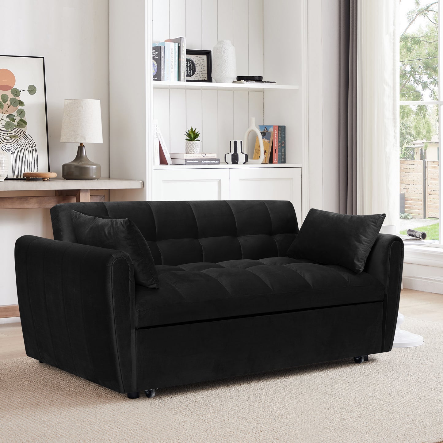 Black velvet tufted sofa bed with two accent pillows on a carpeted floor