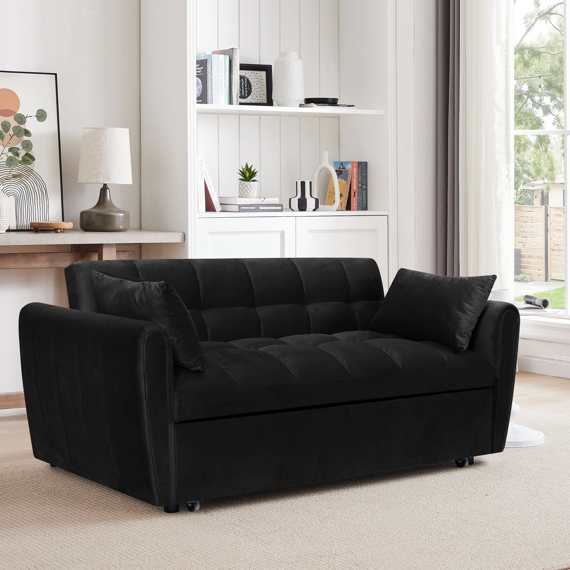 Black velvet tufted sofa bed with two accent pillows on a carpeted floor
