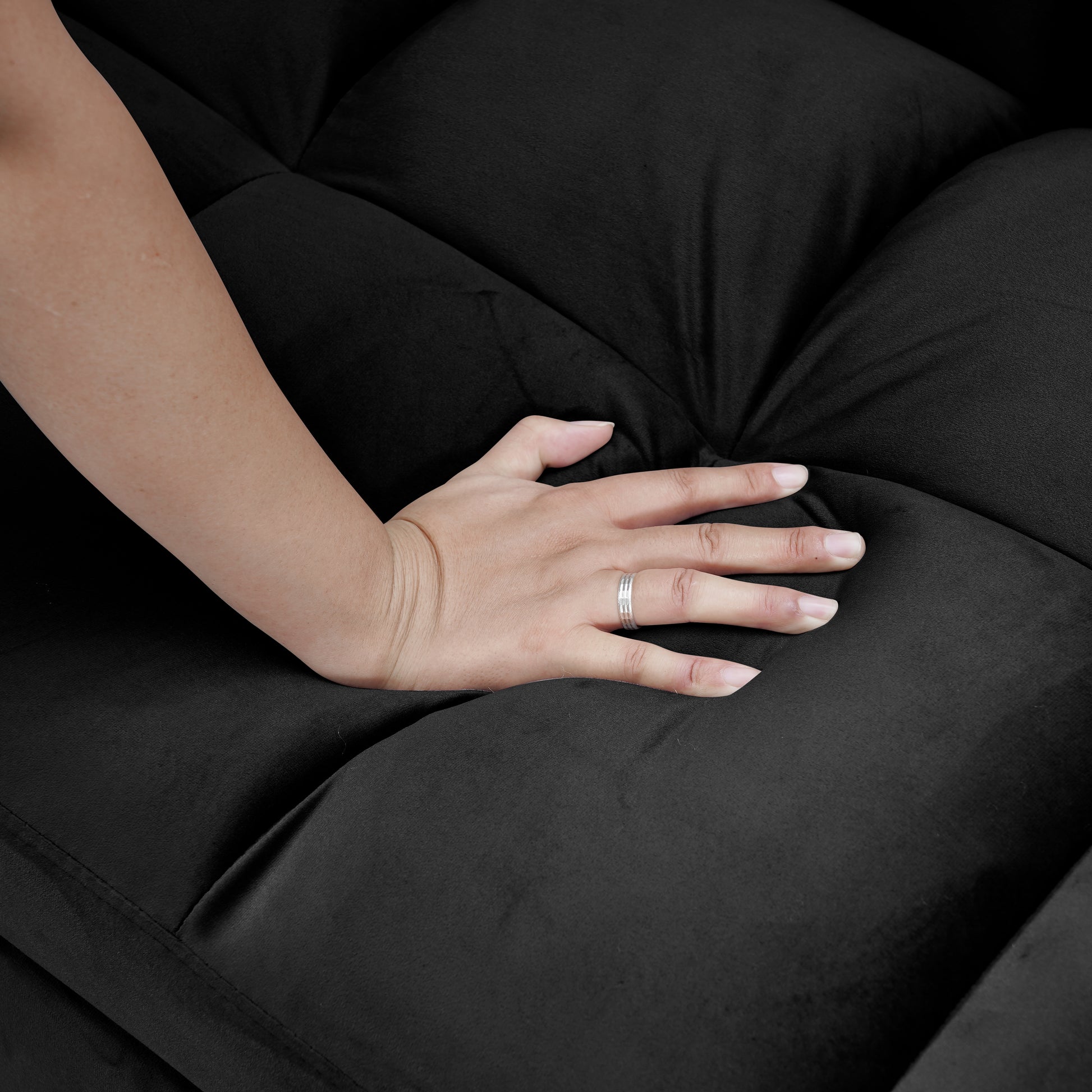 Black velvet sofa with tufted seat and hand for texture preview