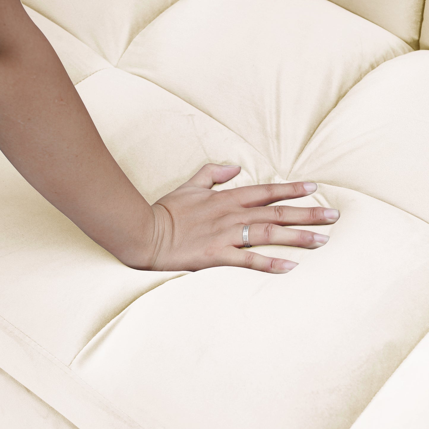 Cream tufted sofa cushion with a hand pressing into its plush surface