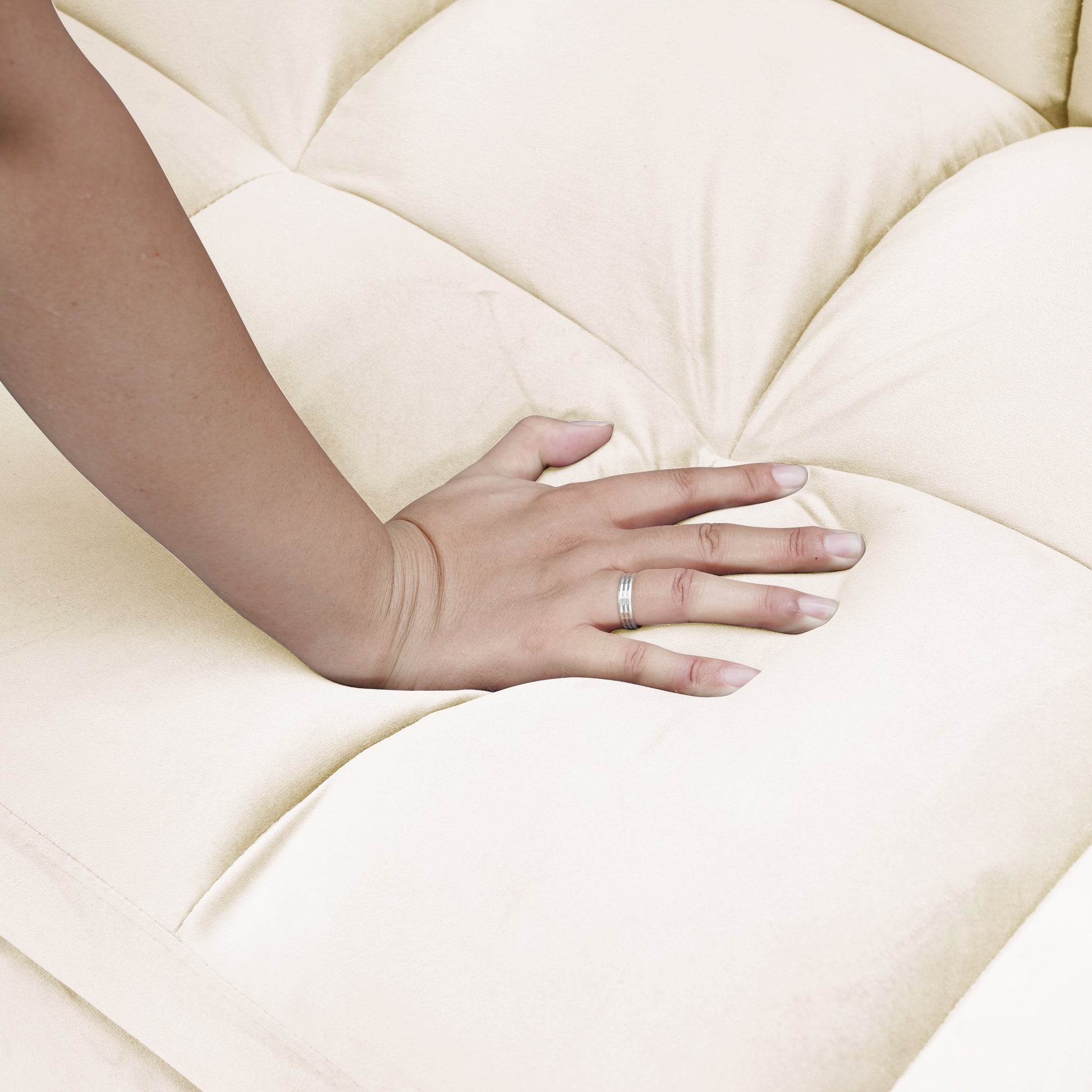 Cream tufted sofa cushion with a hand pressing into its plush surface