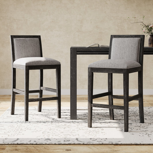 Two gray upholstered bar stools with distressed dark wood frames sit by a table