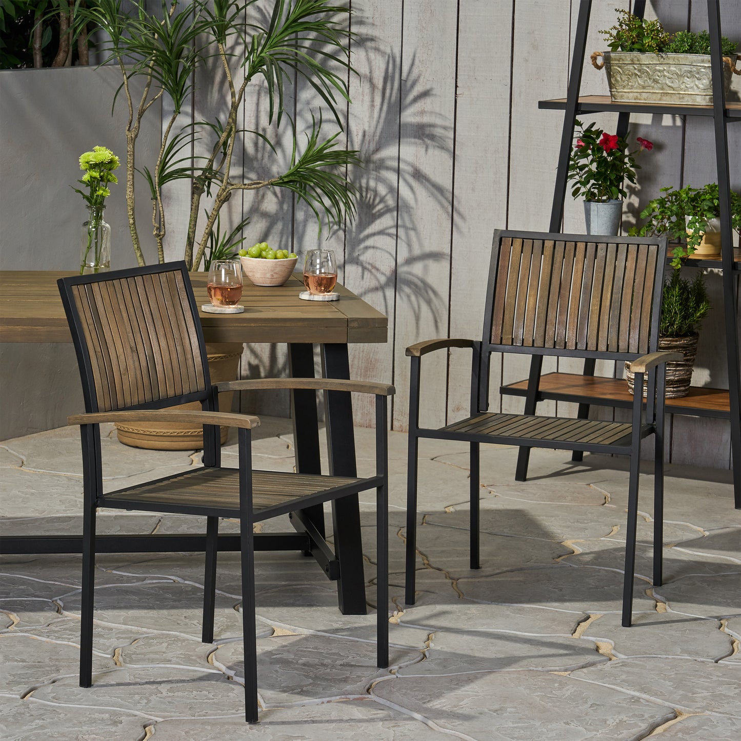 Two black metal outdoor chairs with slatted wood seats and backs
