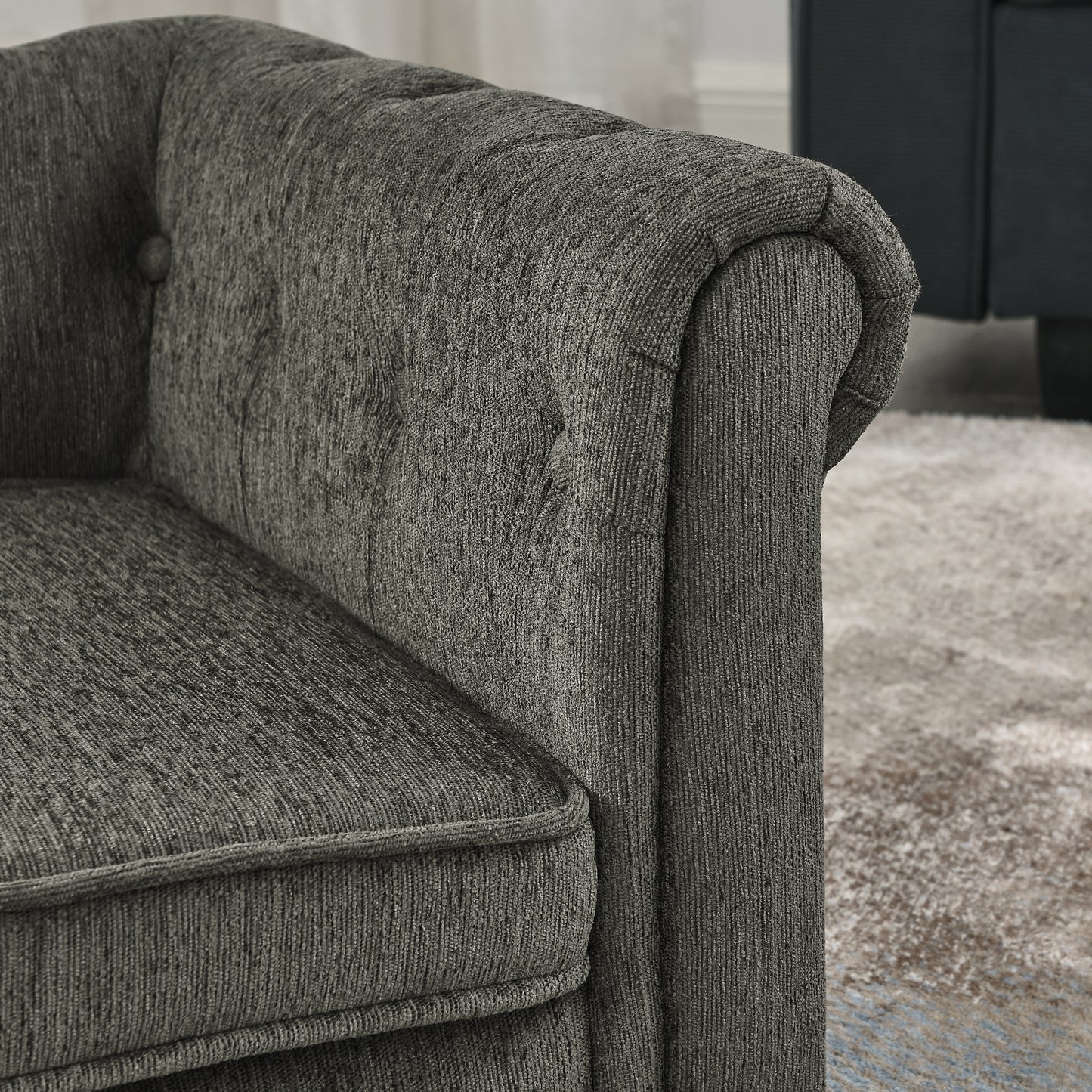 Closeup of a textured dark gray chenille armchair with tufted back detail