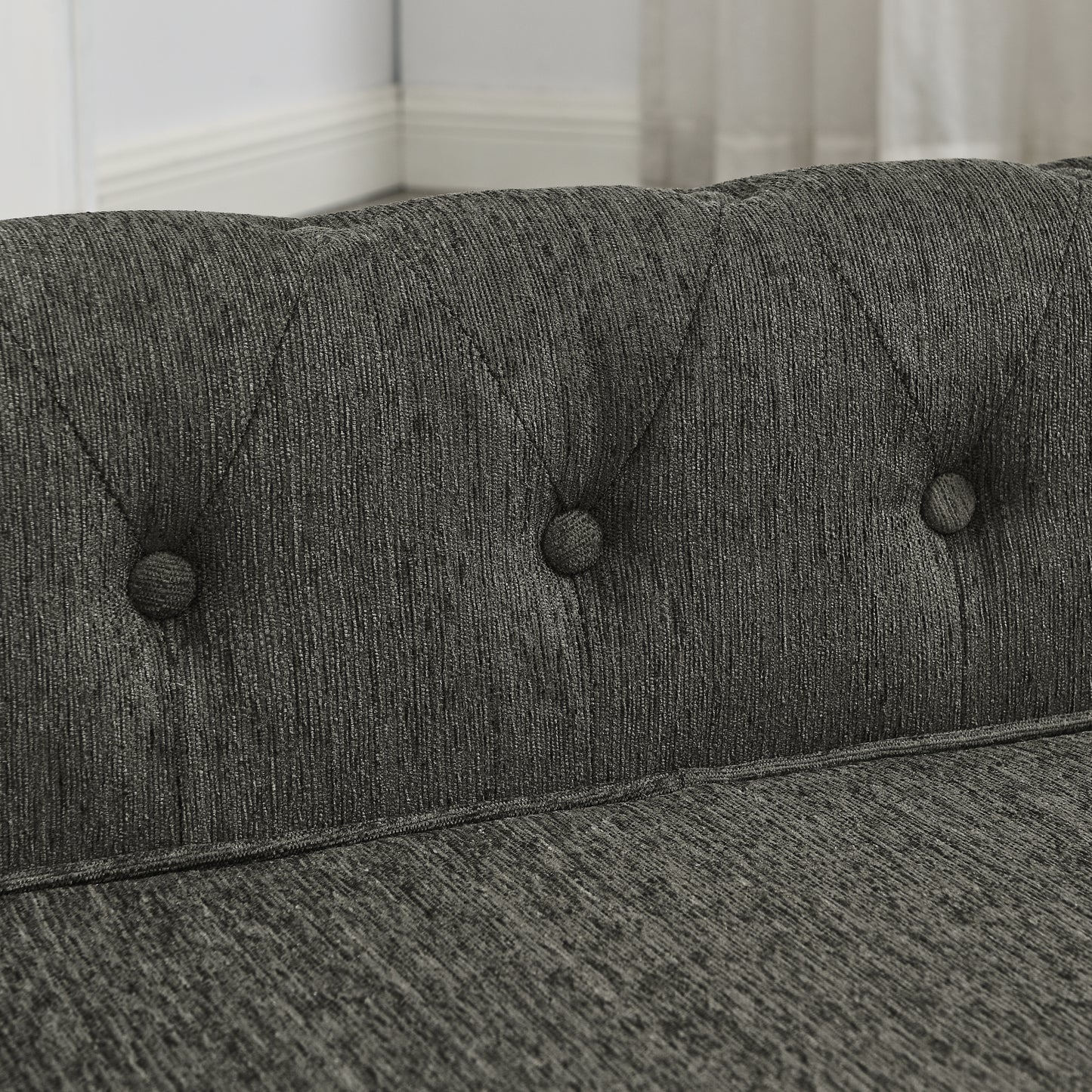 Closeup of dark grey fabric sofa with button tufting and diamond stitching detail