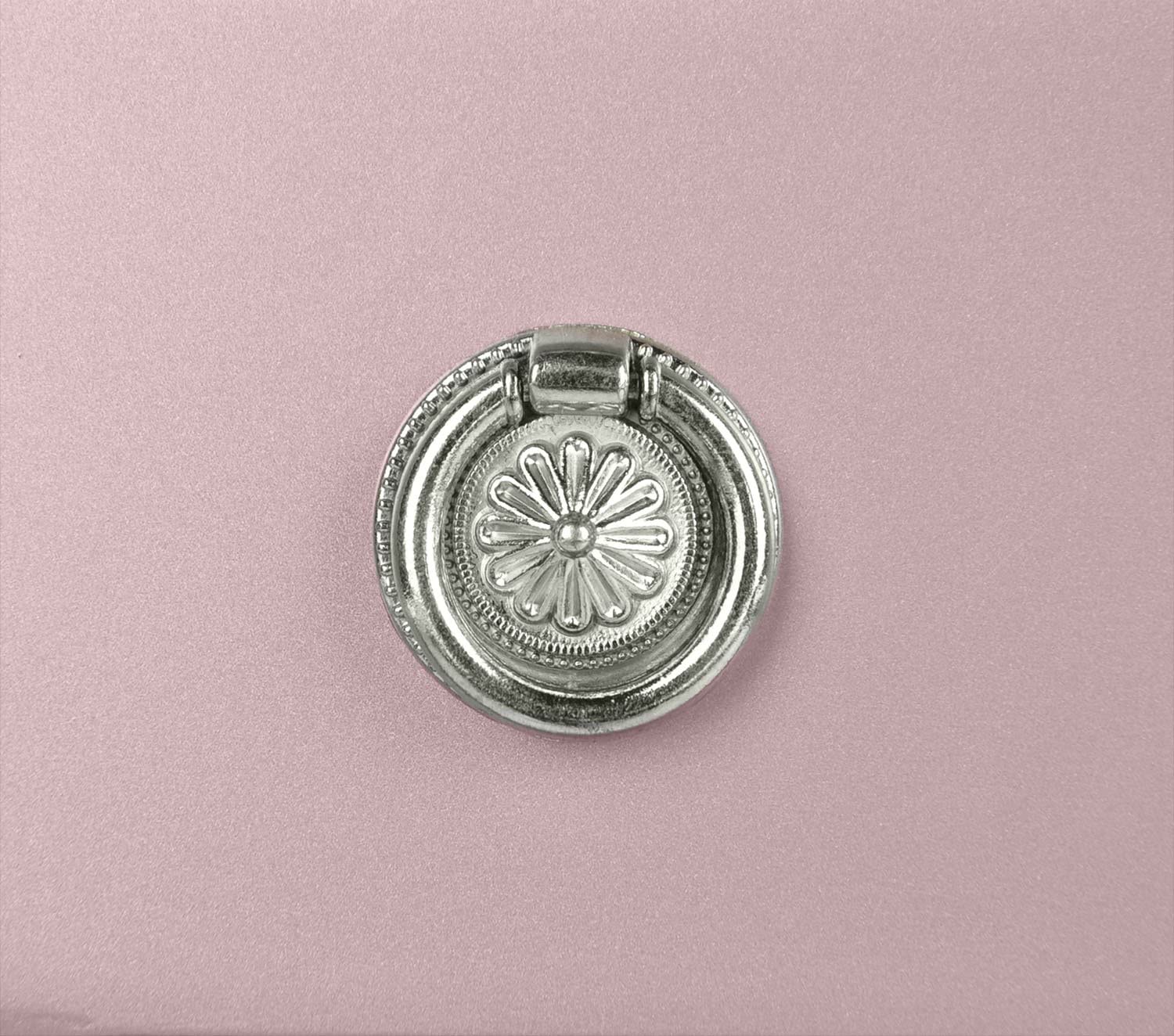 Silver ornate drawer pull with floral design on pink cabinet