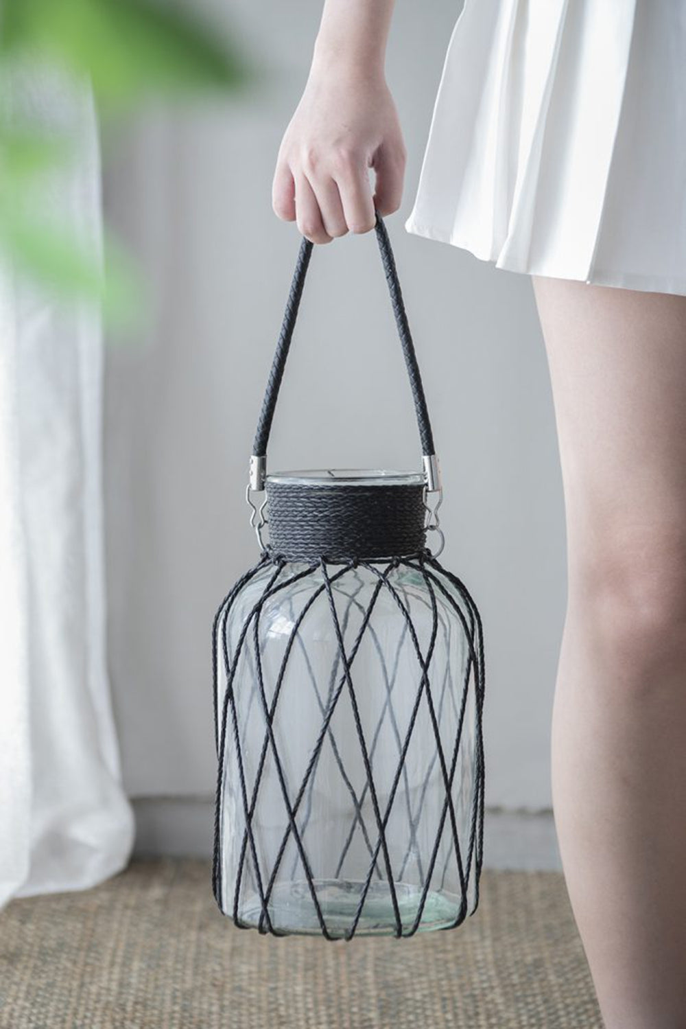 Glass lantern with black rope cage and handle perfect for outdoor patios