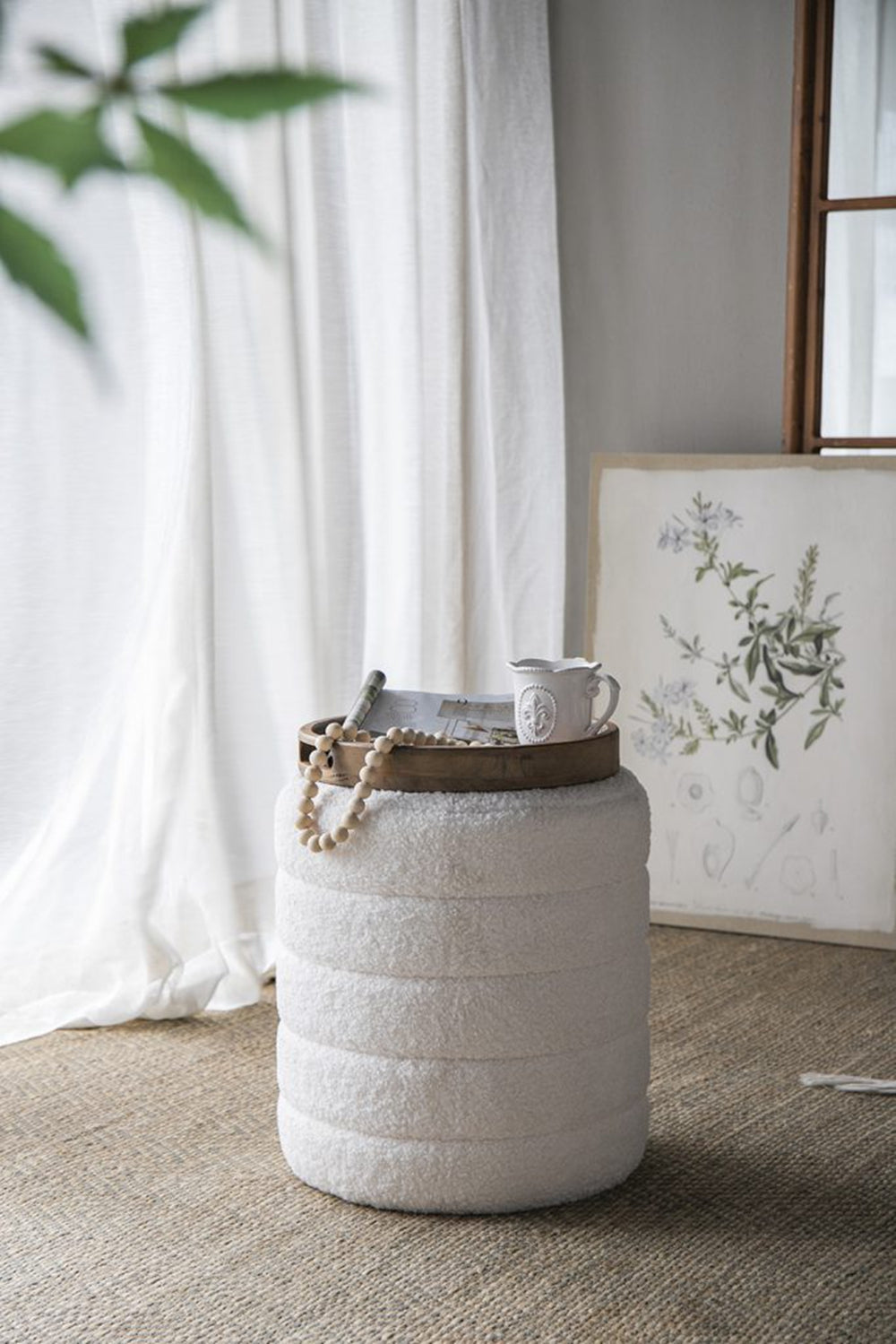 Plush white boucle ottoman with a round wooden tray creating a cozy accent piece