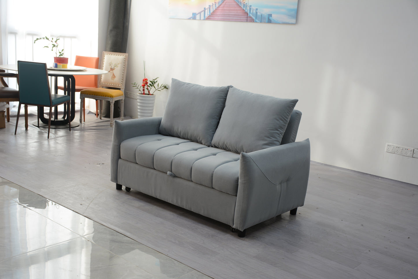 Gray velvet sofa bed with tufted seat cushions and plush throw pillows