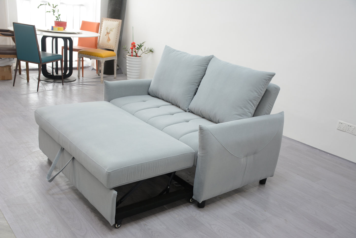 Light blue upholstered sofa bed with tufted seat cushions extended