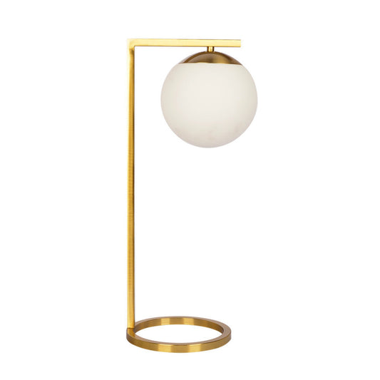 Modern brass table lamp with white globe shade and circular base