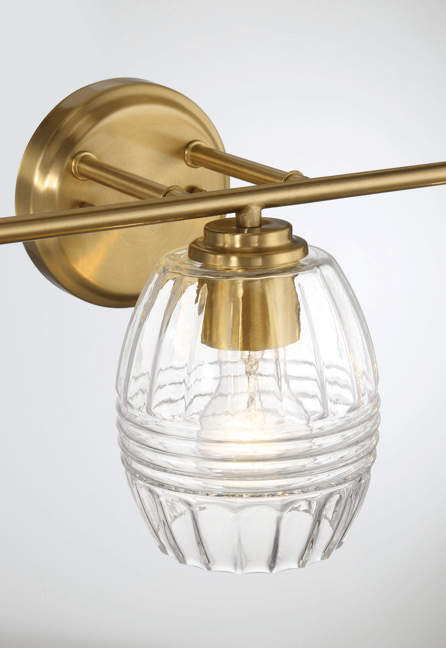 Brass vanity light with a fluted clear glass shade showcasing modern elegance