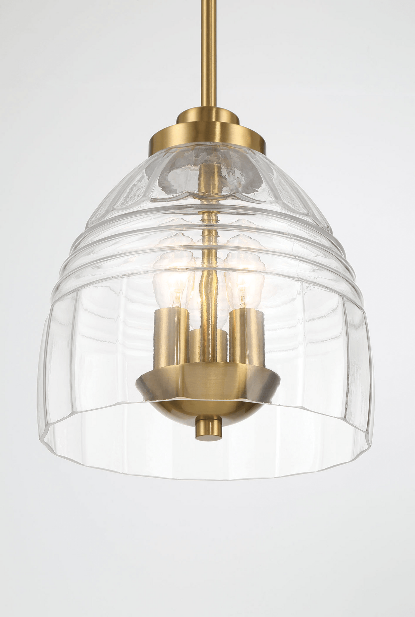 Modern pendant light with brass finish and textured clear glass shade illuminating a home interior